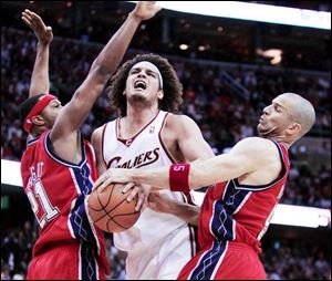 Anderson Varejao is caught between Antoine Wright, left, and Jason Kidd, who ties up the Cavalier. Kidd scored 20 points.
