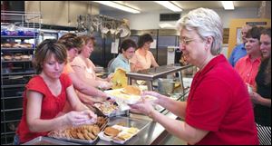 Connie Bricker gets a meal from workers Vicki Sedlak, from left, Lisa Watson, Debbie Rossler, Ellie Patton, and Dianne Bonnough at the Frank Elementary birthday party.