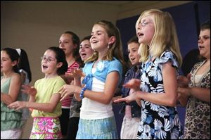 Kelly Ackland, from left in front, Jordan Doore, and Clare Carson, all 10, join other students as the fourth and fith grade chorus sing for the audience at the anniversary kickoff.