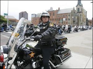 Sheriff s Deputy David Lindhorst watches for traffi c while local motorcyclists ride along Erie Street downtown during the Detective Keith Dressel Memorial Ride and Benefit yesterday.