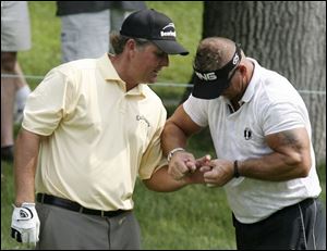 Massage therapist Jim Weathers works on Phil Mickelson's wrist on the 11th hole. That's where Mickelson withdrew.