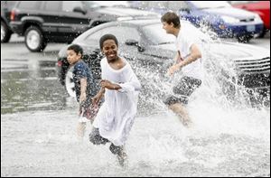 There were some who found fun in the flood, however; Johnnie Barringer, left, Justice Womack, foreground, and
Miguel Neilson enjoy a splash in an Old West End parking lot.