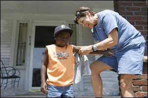 Volunteer Kathy Hussey fi nds she has a little extra responsibility as she wipes some stray paint spots off Damarion Cason, 4, who was visiting his grandmother on Kevin Place.
