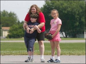 Julie LHeureux helps her son Jason LHeureux wait for a ball to come to him out in the field with his sister, Jessica LHeureux, who's ready to lend a hand if needed. 
