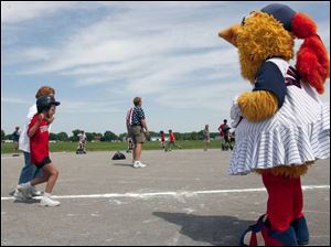 Schyler Young gets some encouragement from Muddonna, one of the Toledo Mud Hen baseball team's mascots who came out for the Miracle League of Northwest Ohio's finals. Schyler is accompanied by volunteer Patricia Pokrzywa on the trip around the bases. 