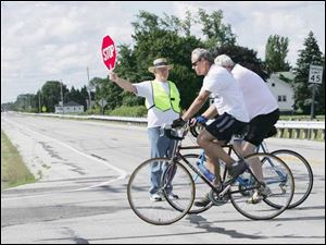 At right, Fred Gerke volunteers as a safety guard along Seaman Road as bicyclists pass through an intersection during a 20-mile bike ride through the heart of Oregon. 