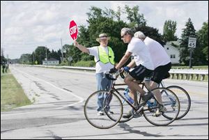 At right, Fred Gerke volunteers as a safety guard along Seaman Road as bicyclists pass through an intersection during a 20-mile bike ride through the heart of Oregon. 