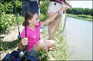 Mariah Panza, 10, of Monroe lands a 12-inch largemouth bass during a free fishing event for youngsters ages 5-13 at Bolles Harbor Mathematics and Science Center on Saturday.