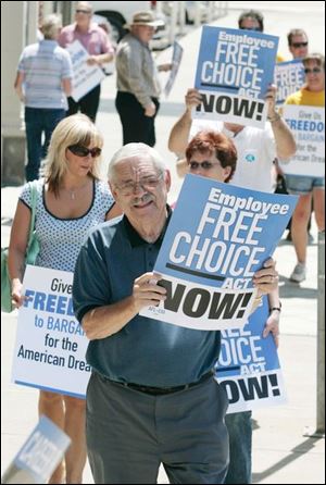 BIZ worker14p 06/13/07 The Blade/Dave Zapotosky Location: Toledo, Ohio Caption: Ron Coughenour, legislative director of the Toledo Area AFL-CIO, center, demonstrates with other workers and activists in favor of the Employee Free Choice Act outside of the Ohio Building Wednesday afternoon.  The group also presented 1,000 postcards to a representative of U.S. Senator George Voinovich who has an office in the building. Summary: Toledo workers and community activist groups will assemble outside the Ohio Building and deliver 1,000 postcards to representives of Senator George Voinovich, who has an office in the building. They are urging support of the Employee Free Choice Act, which is currently pending in the U.S. Senate.