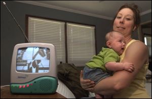 Natalie Meilinger holds her son, Jack, near a baby monitor that has been picking up a transmission from the space shuttle. The monitor's other channel enables her to tune in Jack.