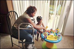 Vena Lampkin, permanently disabled in an accident in Toledo last year, plays with her young daughter Rashyra. 