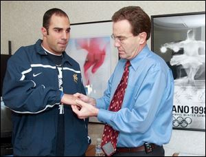 Dr. Roger Kruse, right, examines the throwing hand of former
University of Toledo quarterback Bruce Gradkowski. In 2004,
Dr. Kruse was named Ohio s physician of the year by the state s
athletic trainers. He has been involved in four Olympics.
