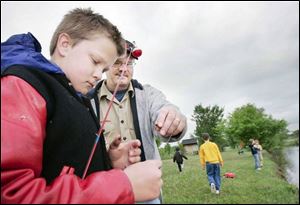 Cubmaster Mike Kleman helps Michael Calcamuggio, 10, during a Boy Scouts fishing outing at a pond in Bowling Green.