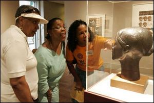 Delores Penn, left, Patricia Hogue, and Karen Sanders, all of Toledo, study the eyes of Elizabeth Catlett's sculpture 'Glory' on exhibit at the Toledo Museum of Art. 