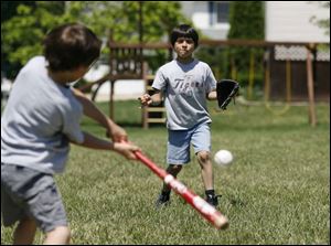 Thanks to his adherence to his treatment plan, Carl Antrassian can play sports, like pitching a ball to his brother Neil, at bat, in a game in their backyard in LaSalle Township, Michigan.