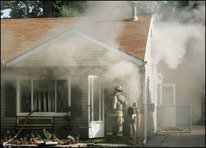 A Toledo firefighter prepares to enter the burning home on Trimble Road yesterday morning. 