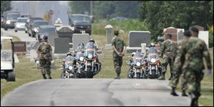 After traveling streets decorated in honor of the pilot killed in Iraq, the funeral procession arrives at the cemetery.