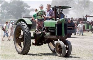 Ben Harbauer, 6, steers one of the family tractors as sister Anna, 3, and dad Jim ride along.