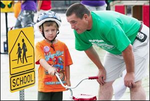 Joey Rambo is decked out in protective headgear as he gets the straight scoop on crossing the street safely from Sylvania Officer Bob Roe during the Sylvania Safety City program. 