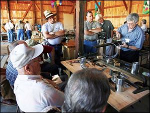 Bill McMillen of Glenmount, N.Y., demonstrates how to make a mug from tin to enthusiasts at Sauder VIllage.