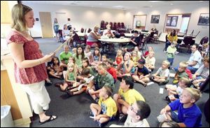 Children's librarian Stephanie Rubley reads a mystery to children before they begin their search for clues during the Library Detective Bureau program at the Ida Branch Library.
