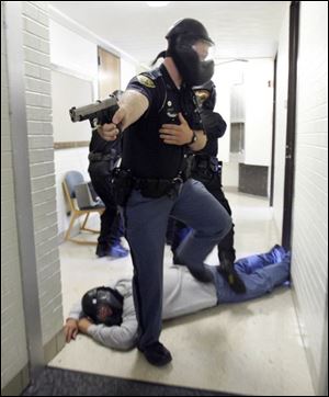 Bowling Green police Patrolman Matt Robinson steps over a  dead bystander  during a training exercise, above, while Sgt. Will Ogden of the Ohio Highway Patrol s Findlay post provides cover behind other law enforcement officers.