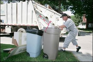 Kertis Reed, a city trash collector, picks up refuse on Goddard Road. After not covering the area last week because of the holiday, trash collectors have two weeks of garbage to pick up.