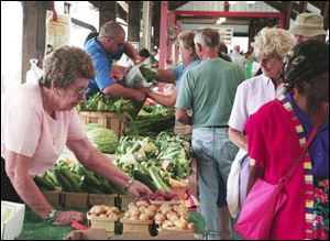 Eleanor Billau of Bedford Township sets out some fresh and tempting vegetables for visitors to the Toledo Farmer's Market. 