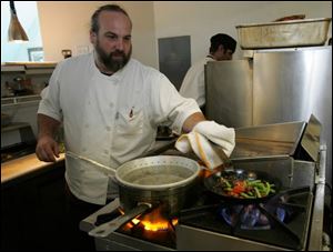 Chef Michael Bulkowski sautes the green beans and cherry tomatoes he purchased locally only hours before. They will be served with Revolver s halibut entree.