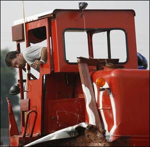Doug Miller checks the damage to his combine after winning the combine demolition derby at the Lucas County Fair.