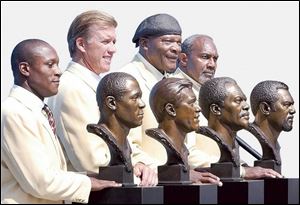 Barry Sanders, from left, John Elway, Carl Eller, and Bob Brown pose with their busts after their induction into the Pro Football Hall of Fame Sunday, Aug. 8, 2004, in Canton, Ohio. 