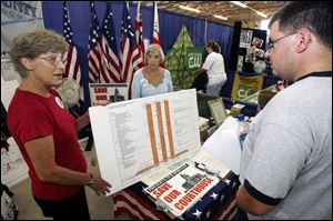 Jackie Fletcher, left, and Nancy Cook of the Save Our Courthouse Committee talk to county fairgoer Brian Tippin of New Riegel, Ohio, about preserving the historic structure in Tiffin.