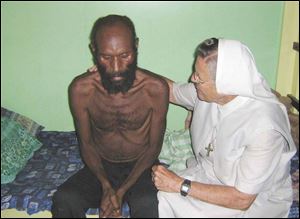 Sister Rose Bernard Groth of the Sisters of Notre Dame comforts an HIV/AIDS patient in Banz, Papua New Guinea.
