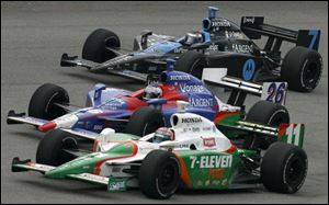 Tony Kanaan, bottom, passes Marco Andretti, middle, and Danica Patrick to take the lead of the Firestone Indy 400 at MIS.