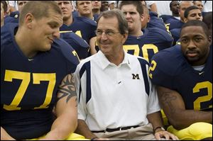 Michigan coach Lloyd Carr finds something funny as he poses for pictures with offensive lineman Jake Long, left, and linebacker Shawn Crable on media day.