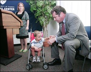 Sen. Sherrod Brown holds the hand of Gavin Taylor, 3, as Gavin s mother, Sheena Taylor, tells of how she had to quit her job to be eligible for Medicaid for her son. Ms. Taylor spoke of her son s health problems during a conference at the University of Toledo Medical School, formerly the Medical College of Ohio, where Mr. Brown promoted the Children s Health Insurance Program. 
