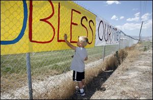 Wylee Sherman, 3, puts a painted handprint to a poster, put up in support of the trapped miners, in Huntington, Utah on Tuesday.