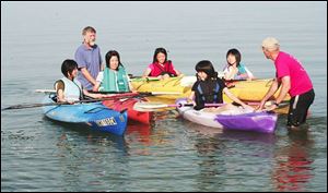 Ted Roberts, rear, and John Lotter, right, help Japanese exchange students, left to right, Megumi Nakao, Asami Oki, Tatsuki Yokonuma, Arika Tanaka, and Saori Mimaki during a kayaking trip on Lake Erie.