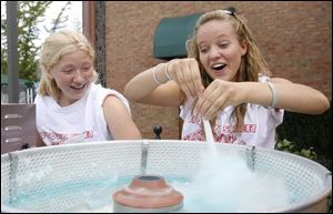 Torey Meinen, right, spins cotton candy as Allie Missler ducks the fine, flying fibers of sugar at the UpTown Street Festival. 