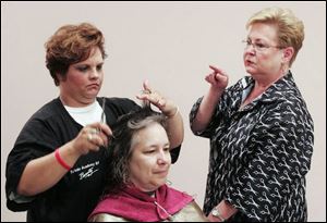 Sherry Smith, left, cuts Lynne Michalak's hair under the supervision of instuctor Rose Stoffel at the Toledo Academy of Beauty South School.