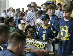 Nine-year-old Drew Buehrer, with hat, and his brother, Grant Buehrer, 12, get autographs from the University of Toledo football team after practice at the Glass Bowl. The boys are from Maumee.