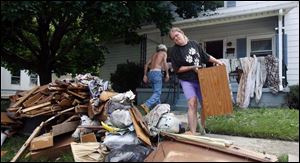 Angela Lowe and her father, Henry Lowe, remove debris from their home on High Street in Findlay. Officials said mold, mosquitoes, and tainted water are among the post-flood dangers.