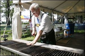 Lou Shindledecker checks the grill to see if it's time to put on the bratwurst he hopes to sell to visitors. 