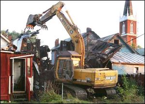 Crews work to demolish one of the two homes destroyed by the early morning fire.