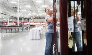 The spaces behind her are expected to be filled with shoppers today as employee Amber Toth makes some last-minute adjustments yesterday to a display before the new Costco in Toledo store opens. 