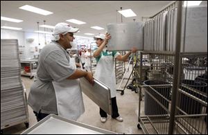Baker Arquimedes Tull, left, and Jena Arduser put away cookie sheets as Toledo's Costco prepares to open.