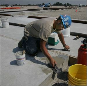 Ryan Ray Shanly, a worker for contractor Rudolph/Libbe, smooths cement for the store's foundation.