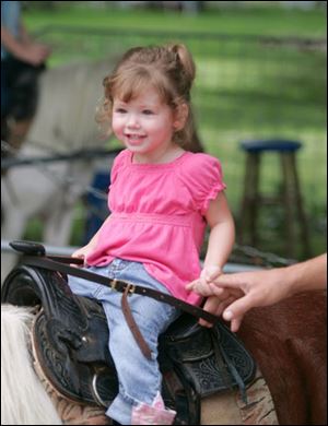 NBRE corn30p  Two-year-old Macy (cq) Creps, of Wauseon, holds on to her dad, Chris, while she rides a pony. The Swanton Corn Festival offers rides, food, music and a car show in Memorial Park in Swanton, Ohio on August 25, 2007.  The Blade/Jetta Fraser.