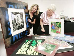 Chamber Marketing Manager Laura Glover, left, and Beth Kaback, a friend of the chamber, preview some of the art to be displayed at the Sylvania Chamber of Commerce's 50th Art Festival.