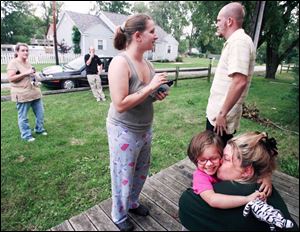Makayla Machcinski gets a hug from neighbor Pam Davis while her mom, Shiloh, and uncle, Randy Logan, stay close at hand.